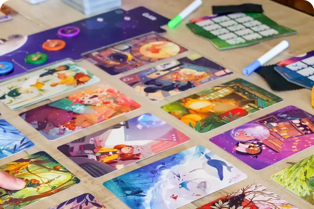 Un colorato gioco da tavolo a tema fantasy con carte illustrate, pedine e fogli di punteggio disposti su un tavolo per una partita strategica.
